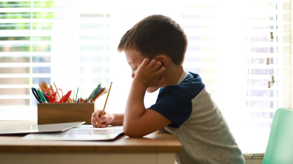child writing in notebook with pencil