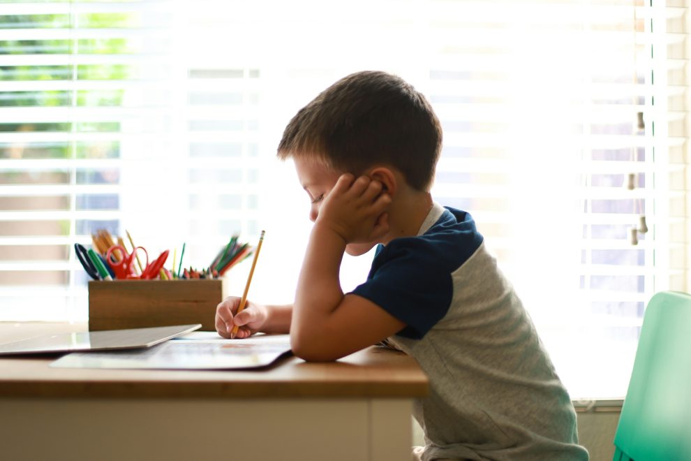 child writing in notebook with pencil