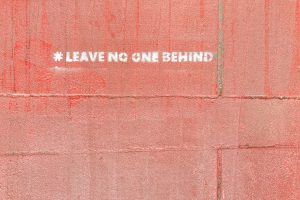 Wall painted with the words "leave no one behind"