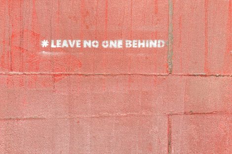 Wall painted with the words "leave no one behind"