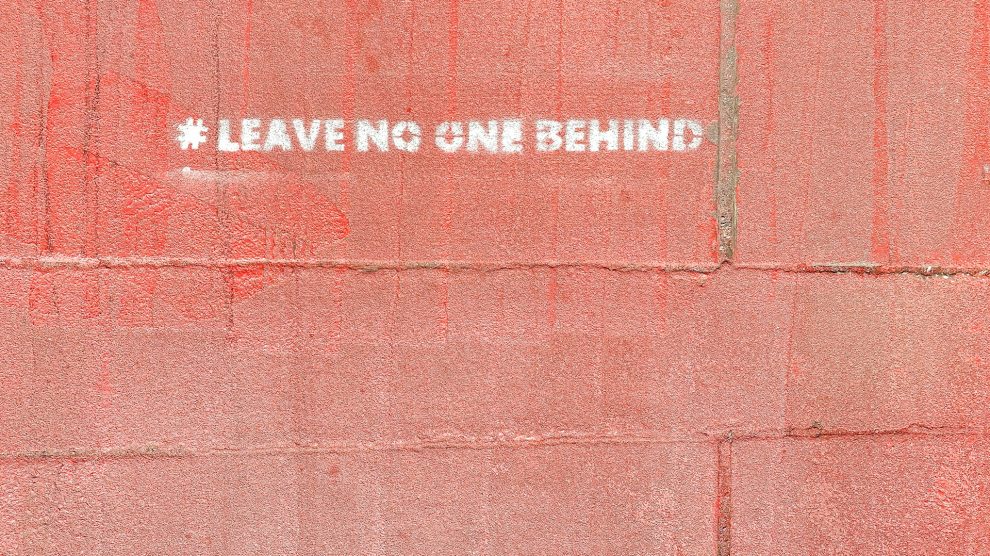 Wall painted with the words "leave no one behind"