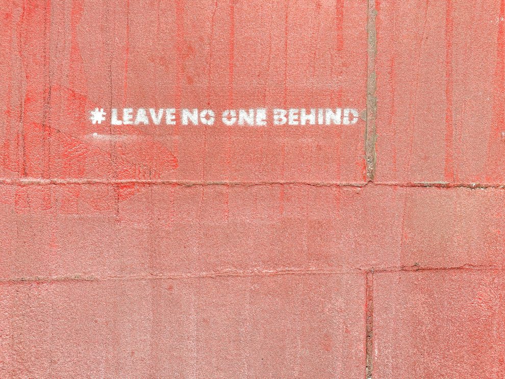 Wall painted with the words "leave no one behind"
