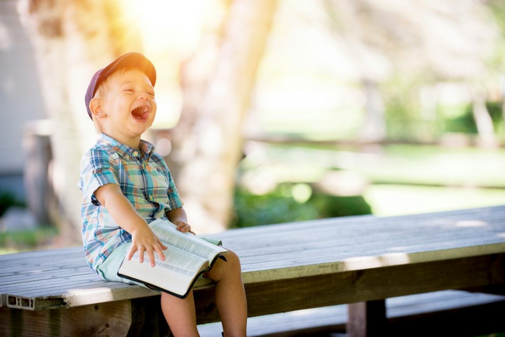 Child sitting on a bench with a bible and smiling