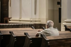 Elderly person sitting alone in a pew