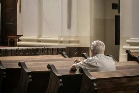 Elderly person sitting alone in a pew