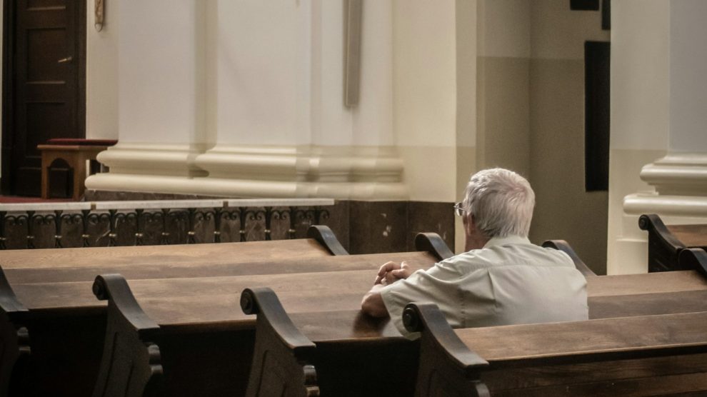 Elderly person sitting alone in a pew