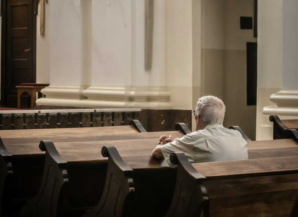 Elderly person sitting alone in a pew