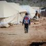 refugee child walking through a tent city