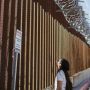 Woman looking up at border wall