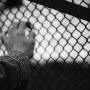 Black and white image of a hand behind chain link fence