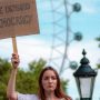 woman-holding-sign-reading-we-demand-democracy